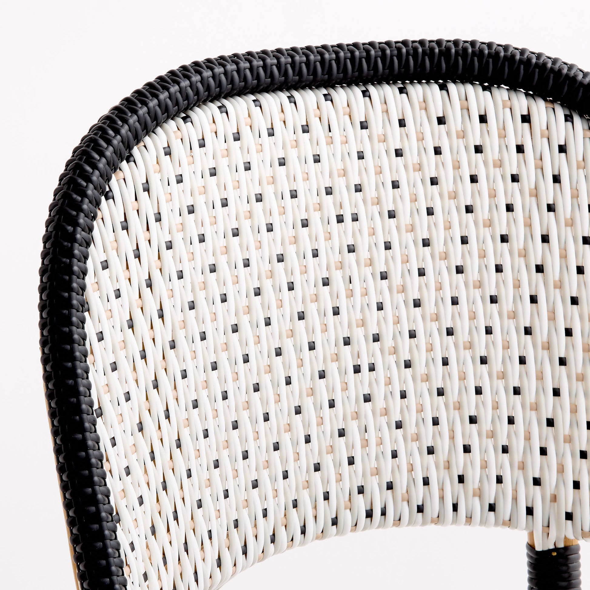 French bistro chair backrest with black and white woven rattan in a polka dot pattern and a solid black border.