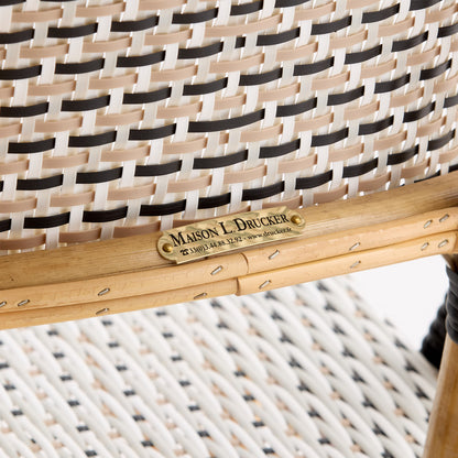 Maison Drucker rattan bistro chair with black, white, and tan woven polka dot pattern and wooden frame.