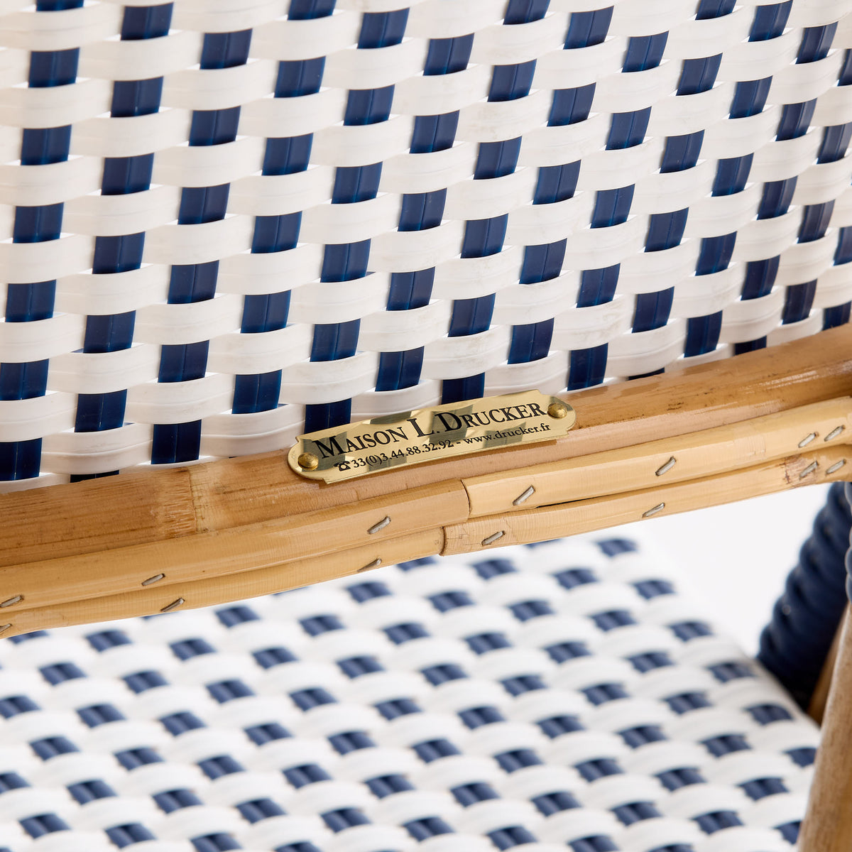Maison Drucker rattan bistro chair with blue and white woven polka dot pattern and brass manufacturer nameplate.