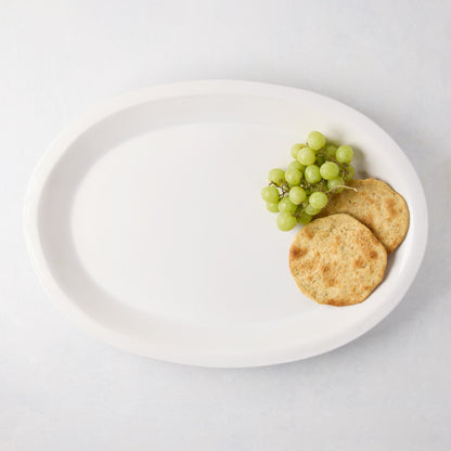 White Ravello Large Oval Stoneware Serving Platter with raised edge, holding grapes and crackers.