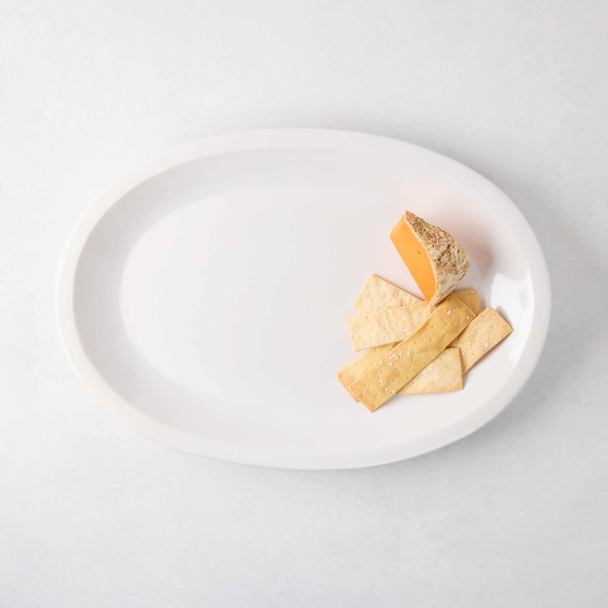 Ravello Small Oval Stoneware Serving Platter in white glaze with cheese and crackers.