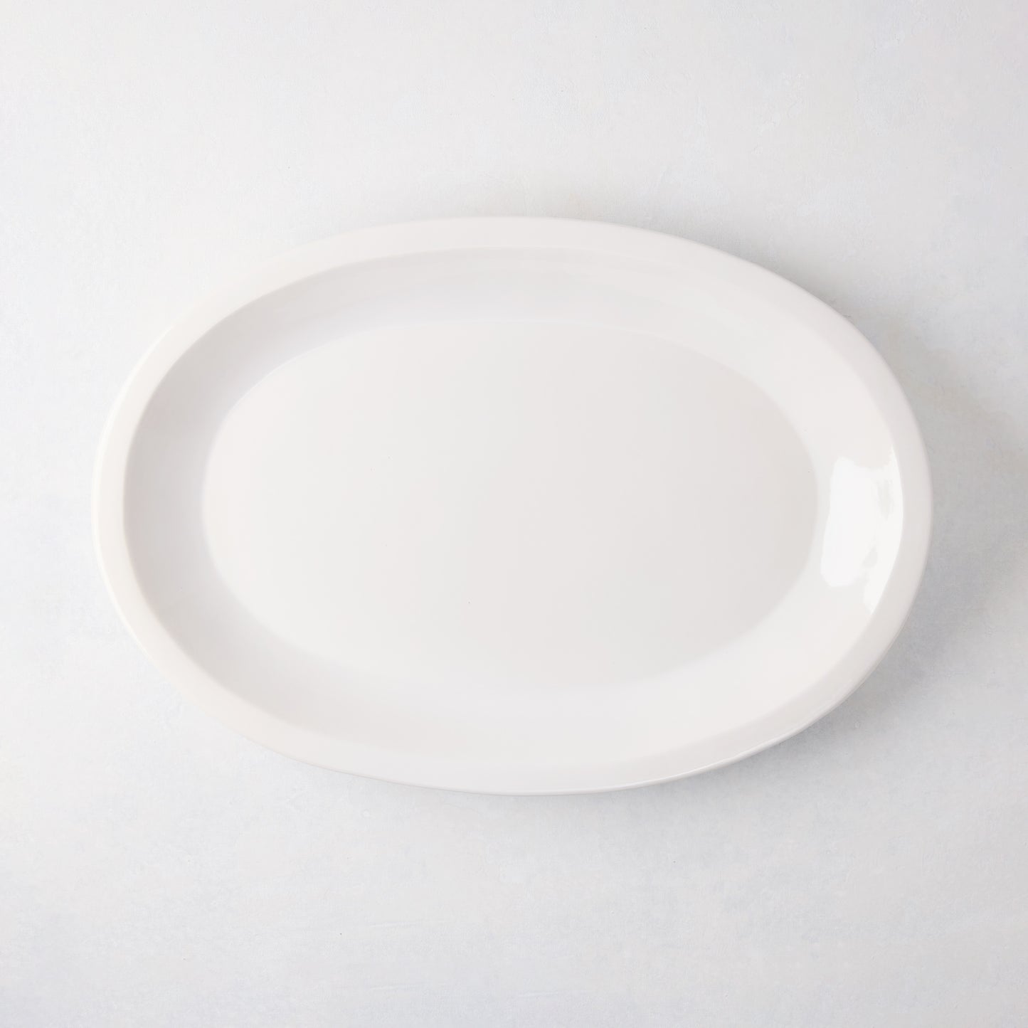 White Ravello Small Oval Stoneware Serving Platter with raised edge, 18.3"L x 12.8"W.