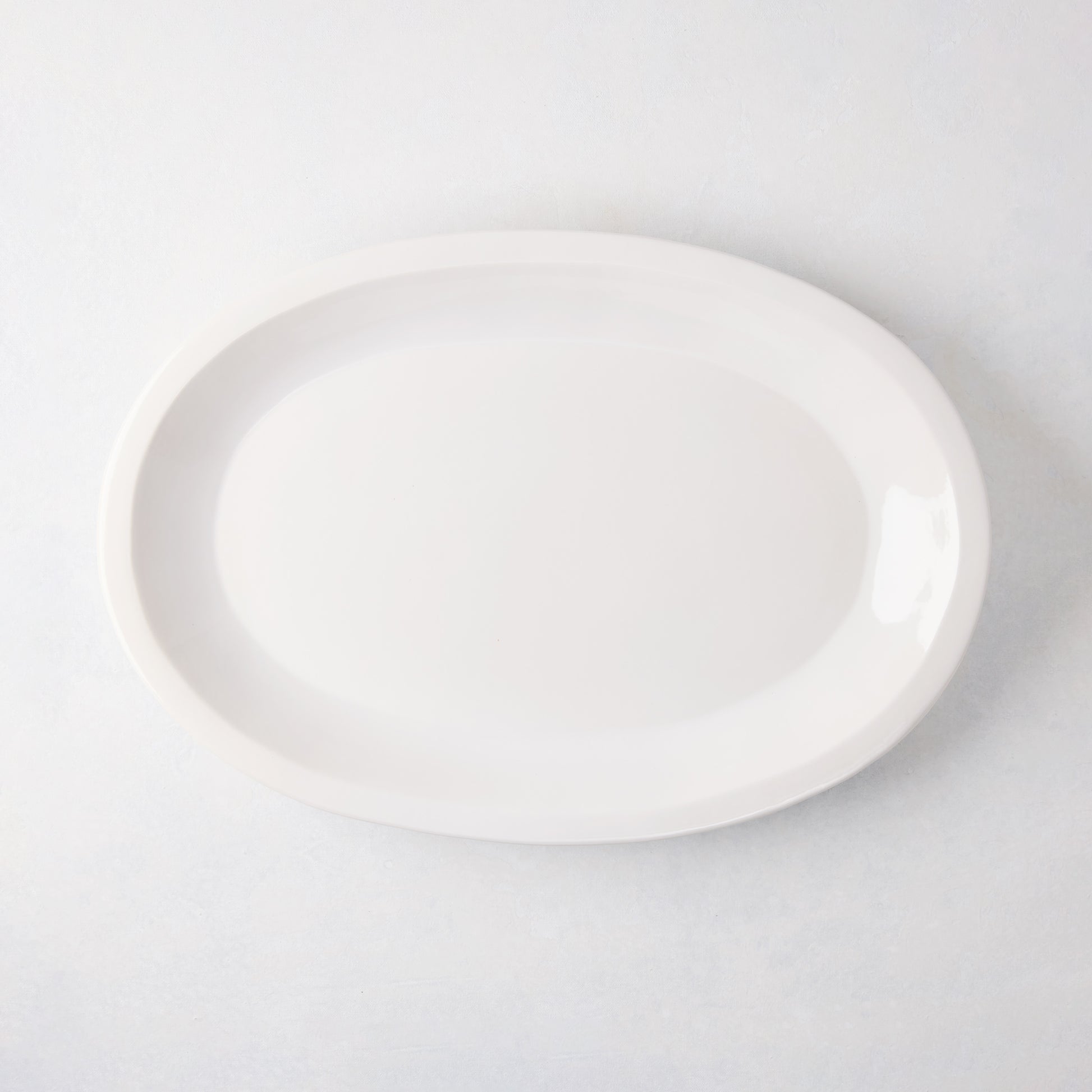 White Ravello Small Oval Stoneware Serving Platter with raised edge, 18.3"L x 12.8"W.