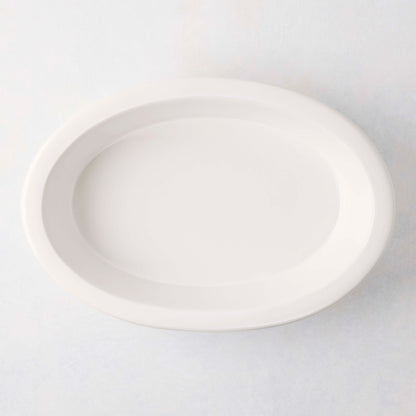 White Ravello Stoneware Oval Baking Dish, 13.6"L x 9.25"W, with an oversized lip.