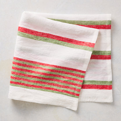 Folded linen napkin with red and green candy cane stripes on a white background.