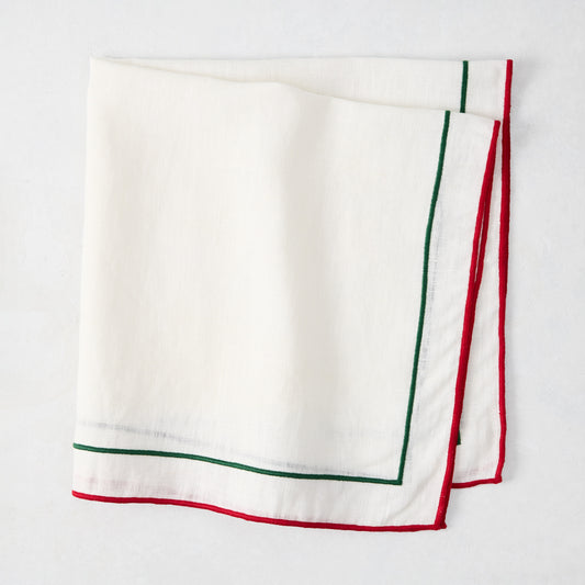 White cotton napkin with red and green double line embroidered border, folded.