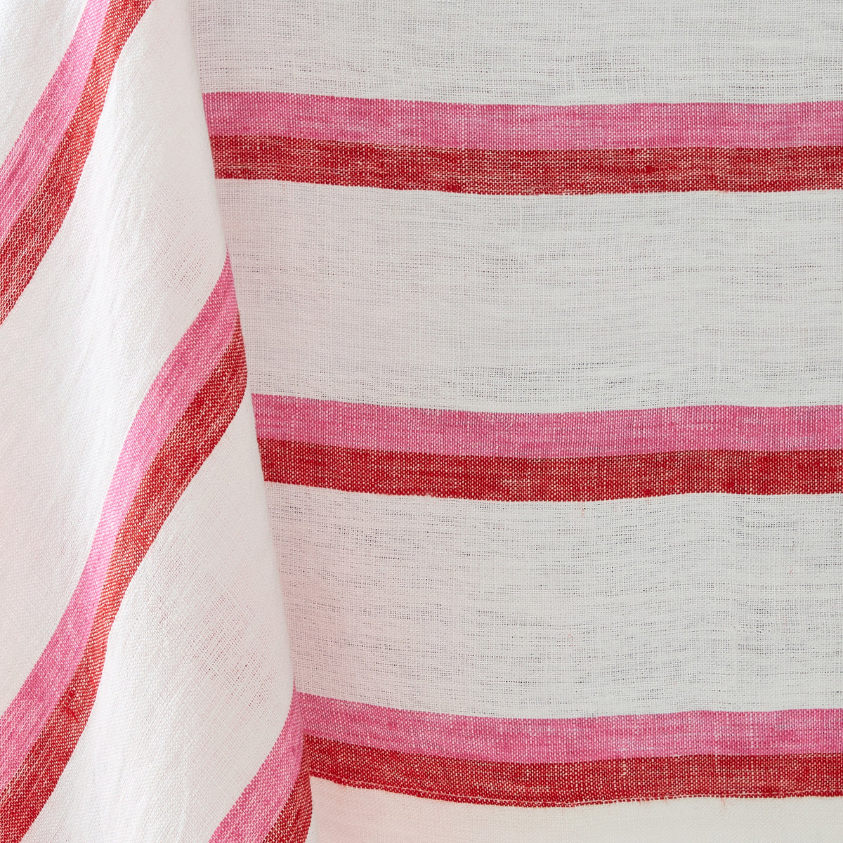 Red and pink candy cane striped linen tablecloth with a textured, woven fabric finish.
