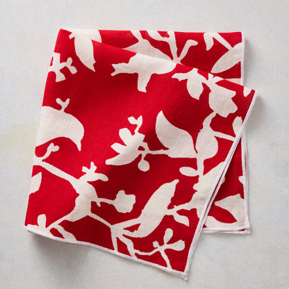 Folded red linen napkin featuring a cream-colored botanical branch and floral print pattern.