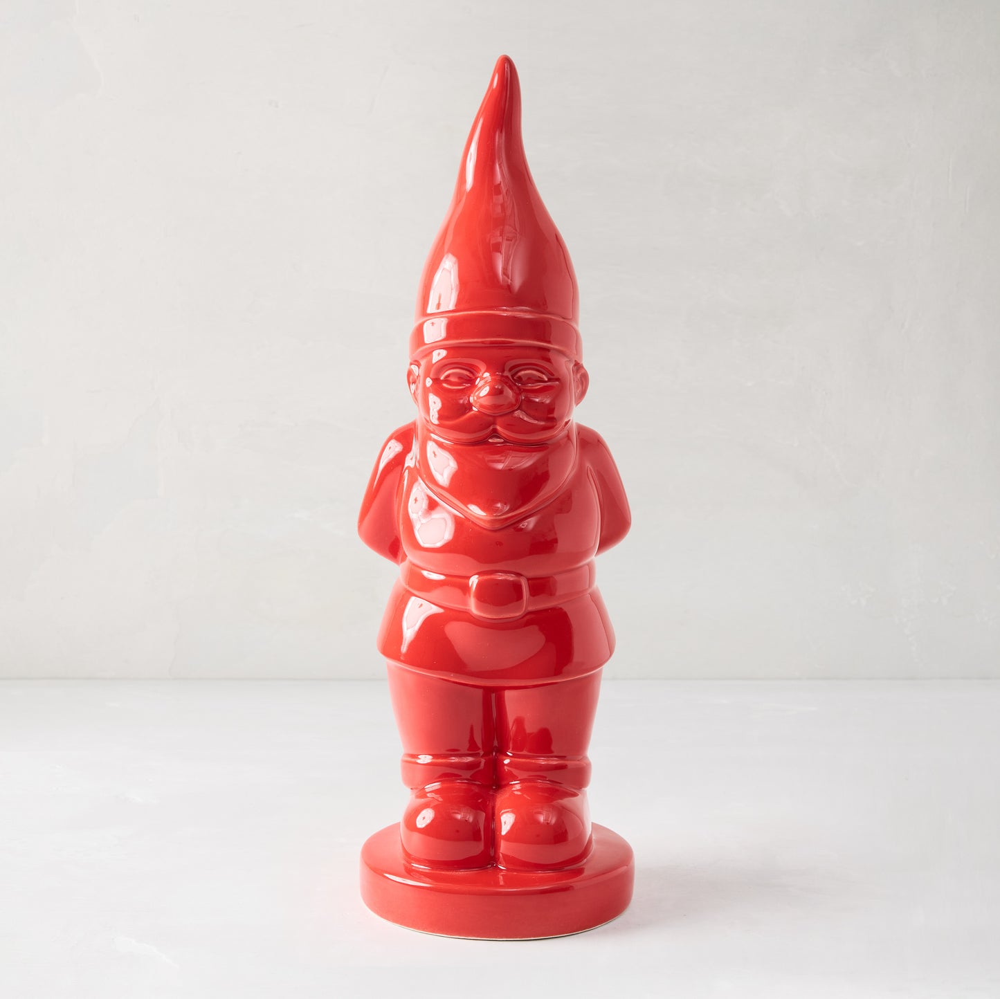 Tall, glossy red ceramic holiday gnome with pointed hat, beard, belt, and boots.