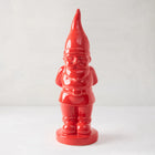 Tall, glossy red ceramic holiday gnome with pointed hat, beard, belt, and boots.