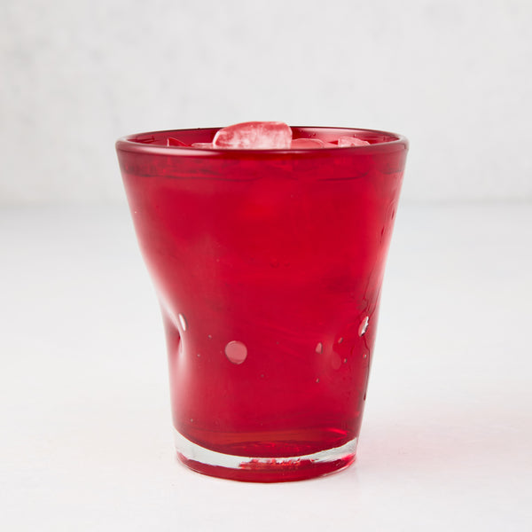 Red Henri 8 oz. mouth-blown glass with ice, showing unique imperfections and air bubbles.