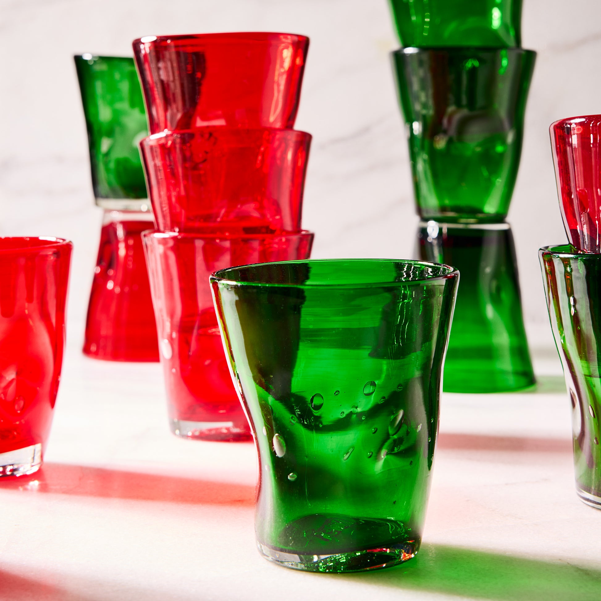 Handmade red and green Henri mouth-blown glass tumblers with unique imperfections and air bubbles.