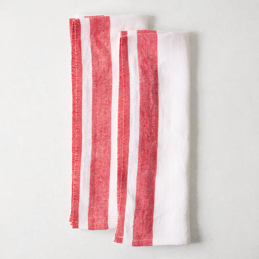 Set of two folded 100% linen hand towels in white with red herringbone stripe borders, 30 by 20 inches.