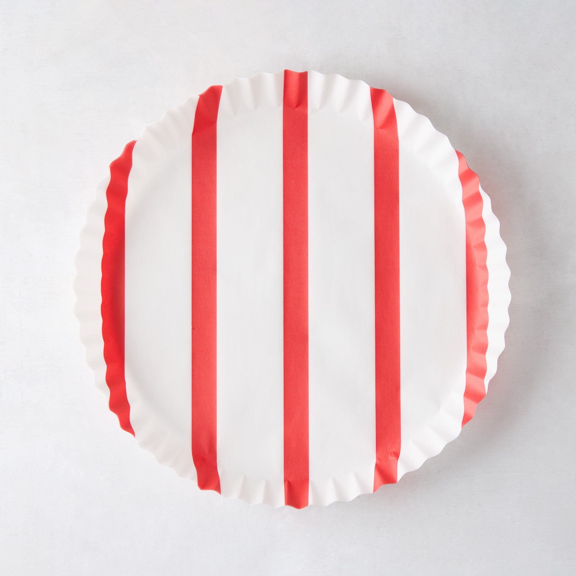 Round white parchment liner with vertical red stripes and ruffled edges.