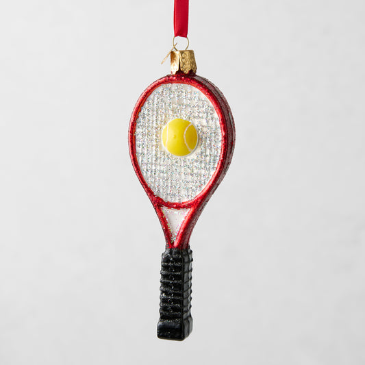Red glitter tennis racquet Christmas ornament with a yellow tennis ball, black handle, and red ribbon.