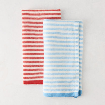Folded red and white ticking stripe linen napkin next to a blue and white striped napkin.