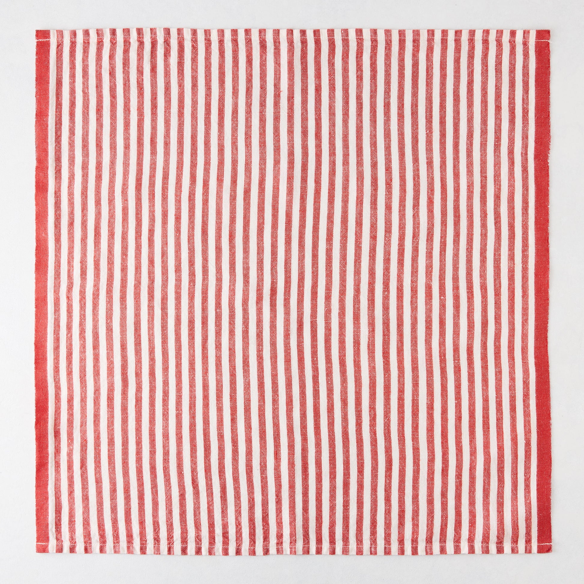 Red ticking stripe linen napkin, 21" square, with thin red and white stripes and a thicker red border.