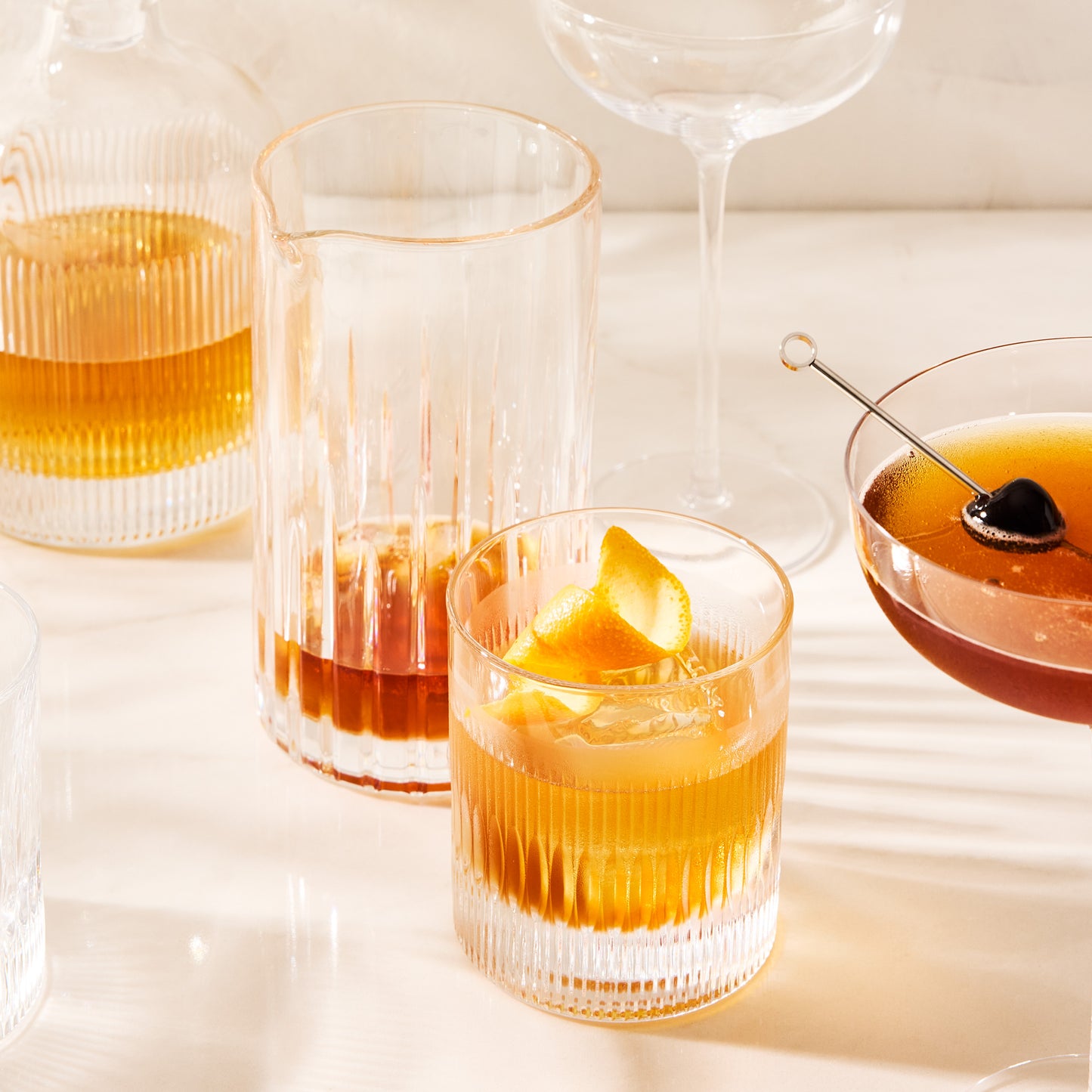Clear Regent Eco-Crystal Double Old-Fashioned Glass with a drink, orange peel, and ice, next to other barware.