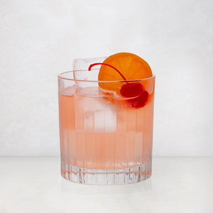 Regent Eco-Crystal Double Old-Fashioned Glass with a pink cocktail, ice, orange slice, and cherry.