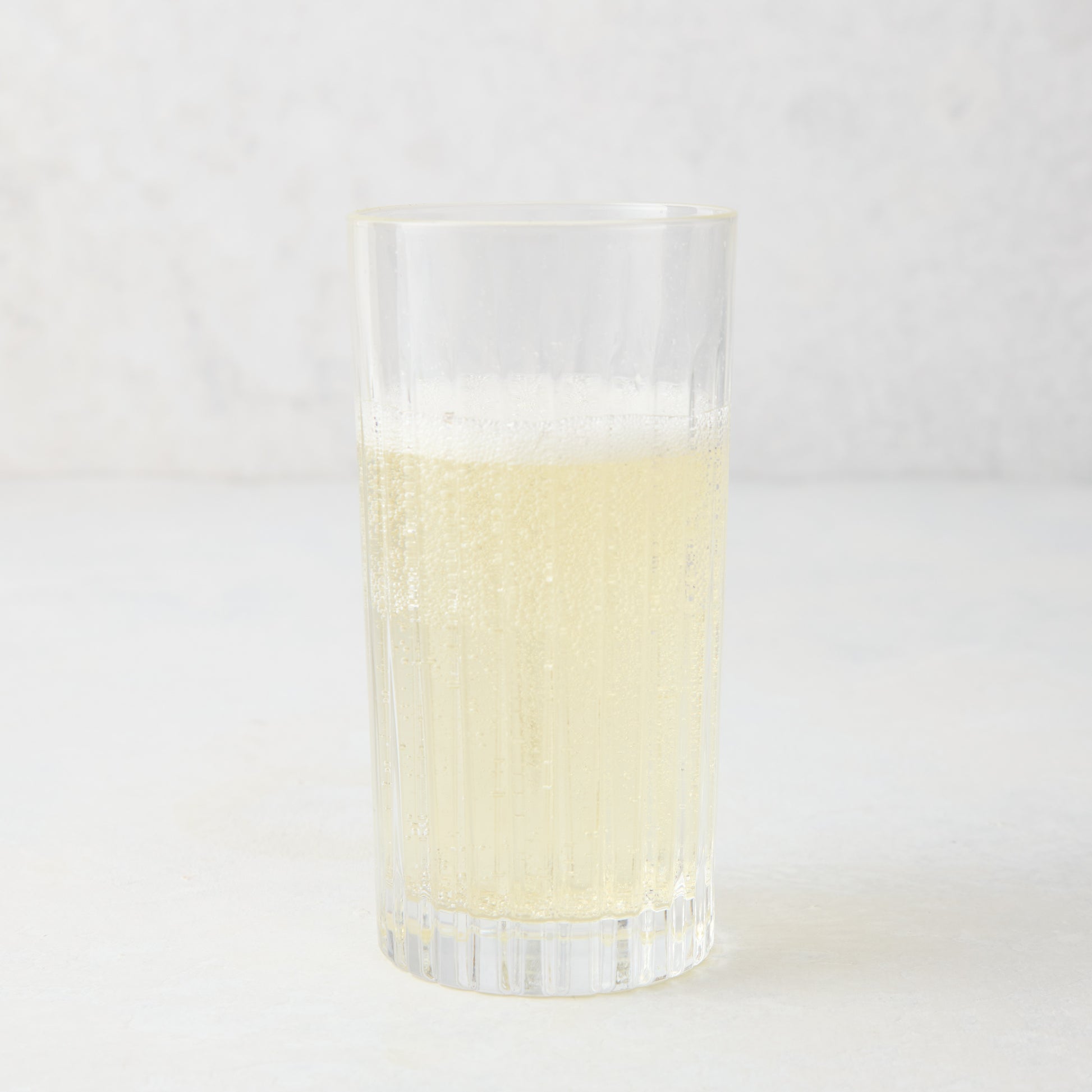 Regent Eco-Crystal High Ball Glass, clear, sleek, slender, with a bubbly light yellow drink.