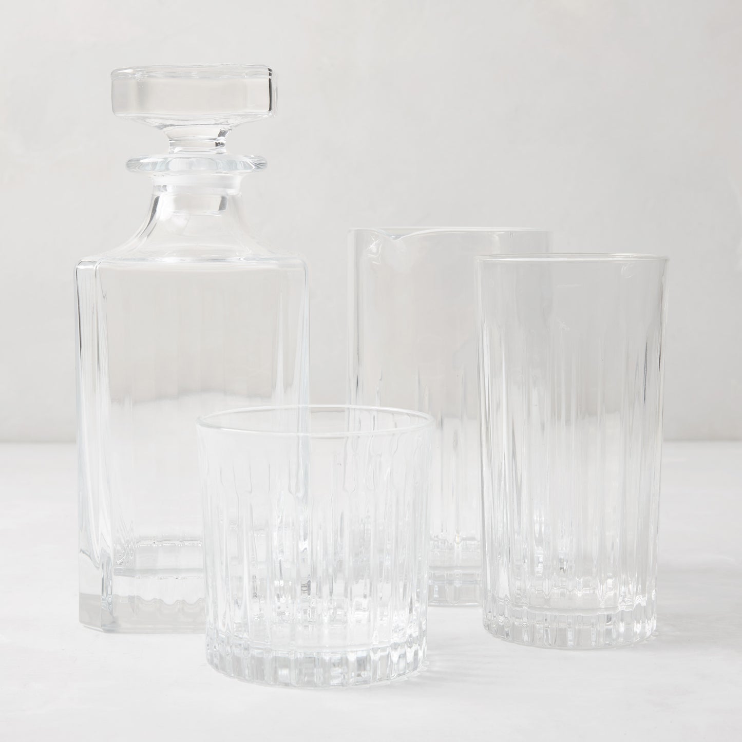Regent Eco-Crystal Mixing Glass and matching decanter with two ribbed drinking glasses on a white surface.