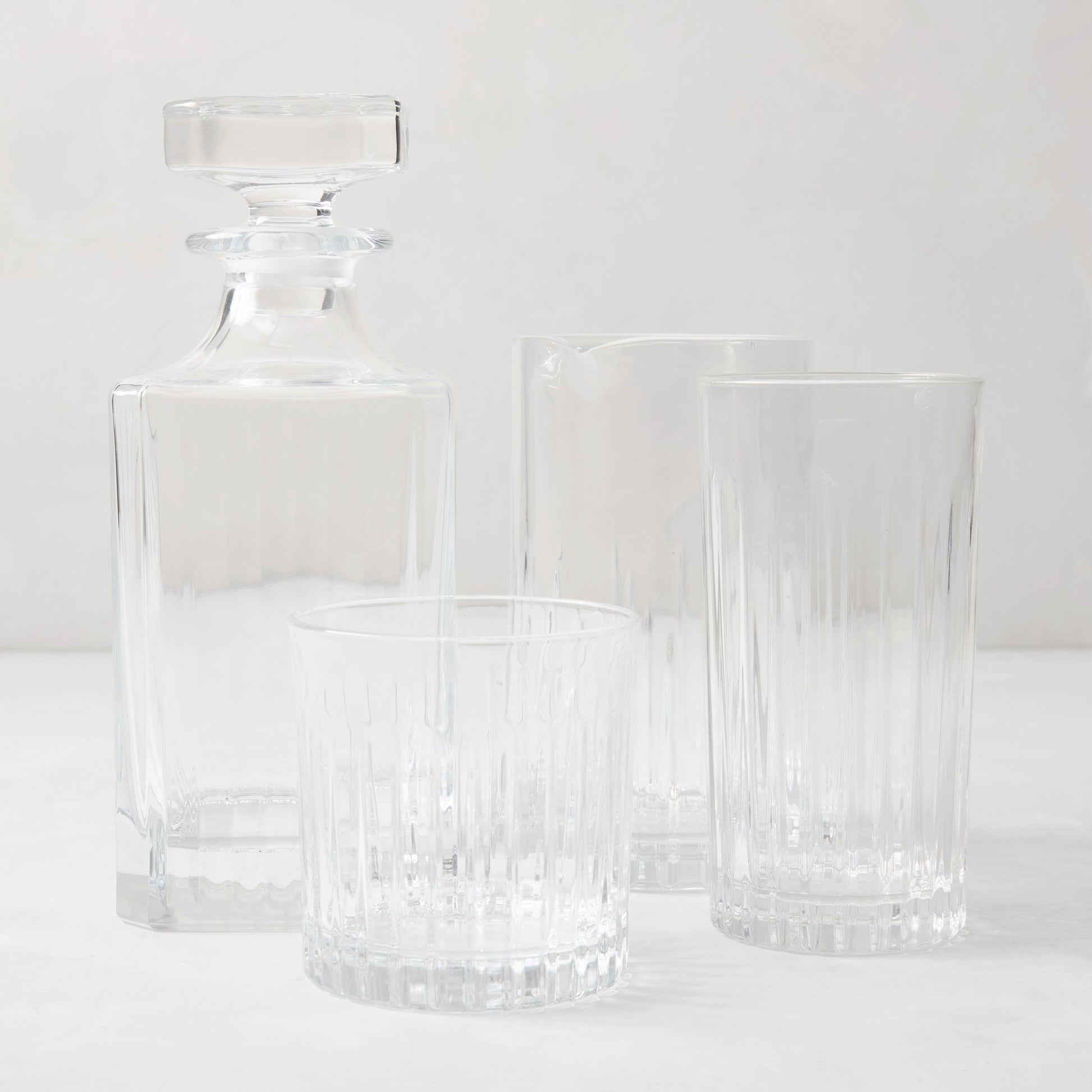 Regent Eco-Crystal Mixing Glass and matching decanter with two ribbed drinking glasses on a white surface.