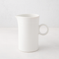 Creamy white ceramic pitcher with a simple ring handle and spout.