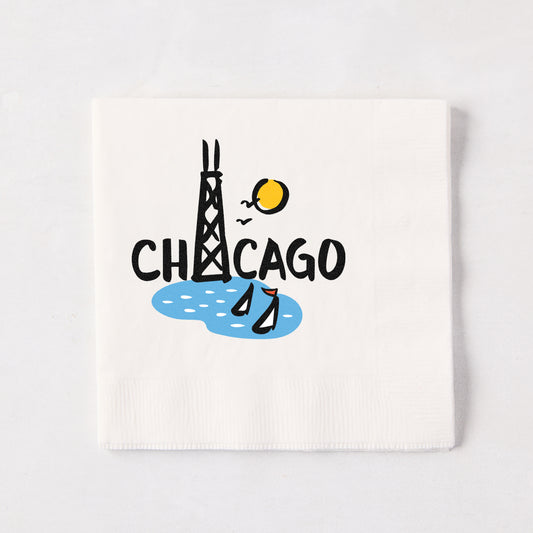 White 5.5-inch square cocktail napkin with a Rob Wilson hand-drawn Chicago skyline illustration in black, blue, and yellow.