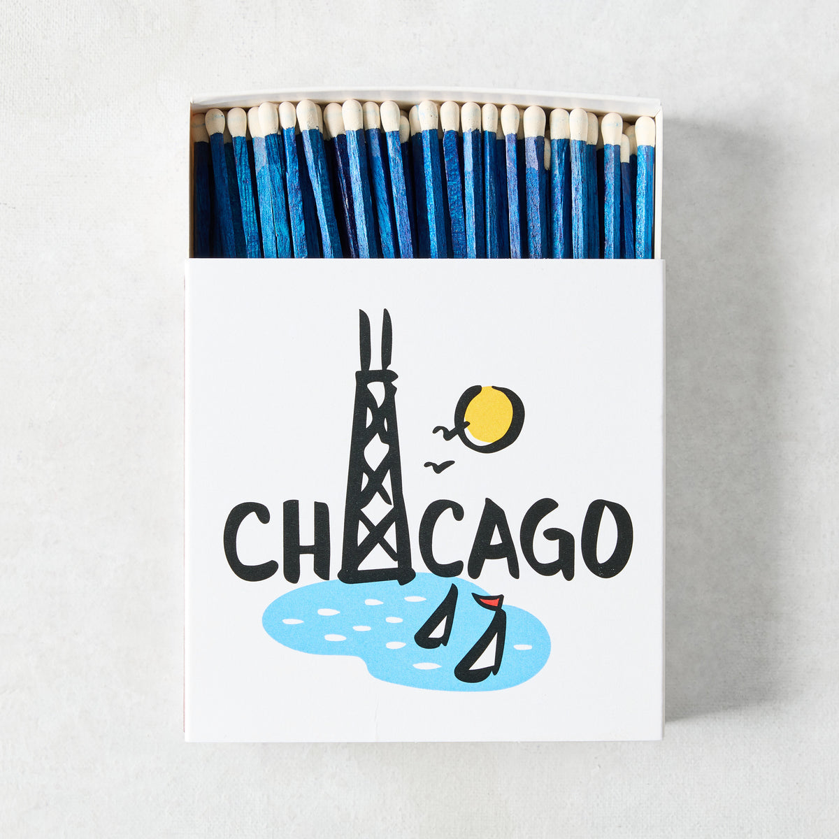 Oversized box of blue-tipped matches featuring a Rob Wilson Chicago illustration with the Hancock Tower and sailboats.