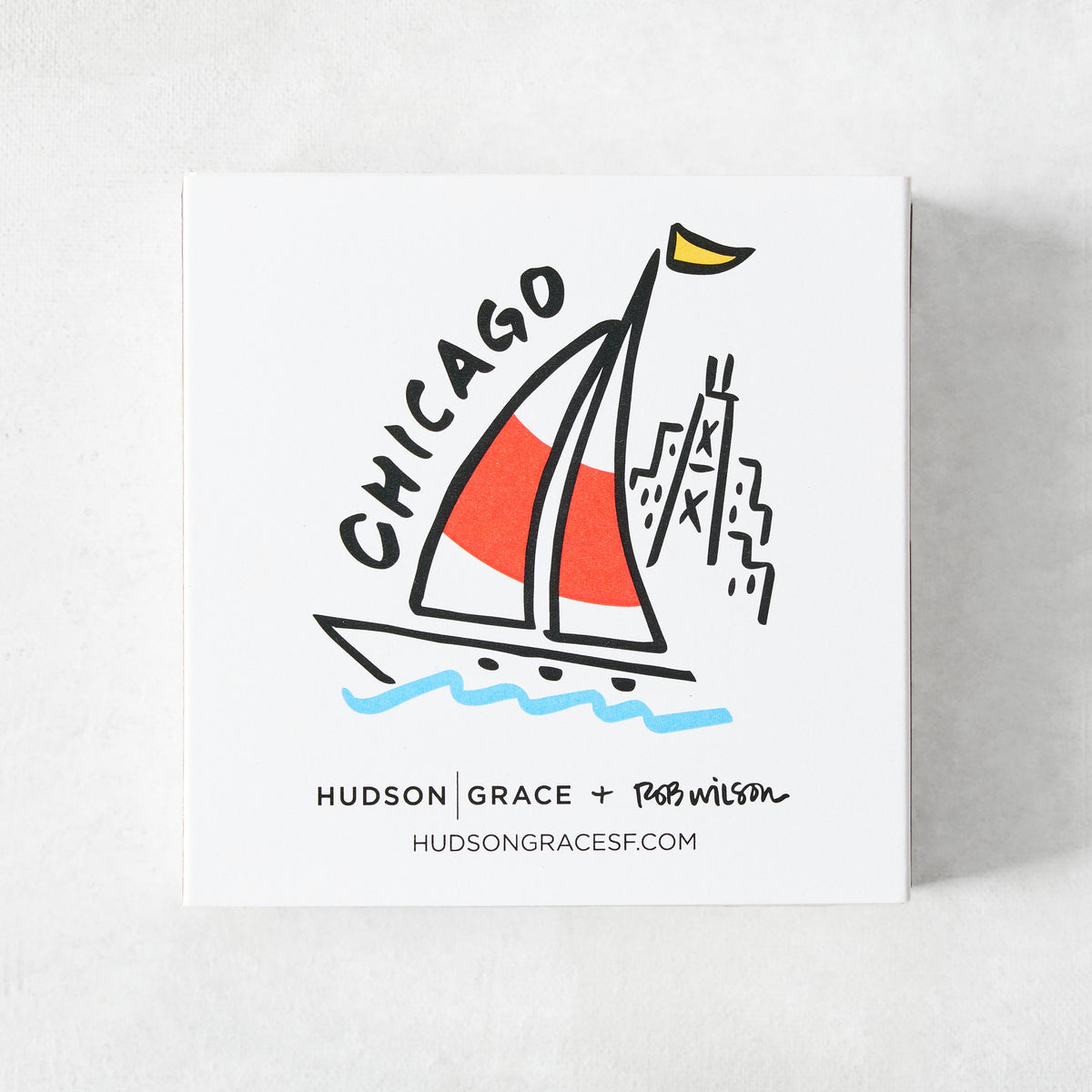 White square matchbox featuring a Rob Wilson Chicago illustration of a sailboat and the Hancock Tower.