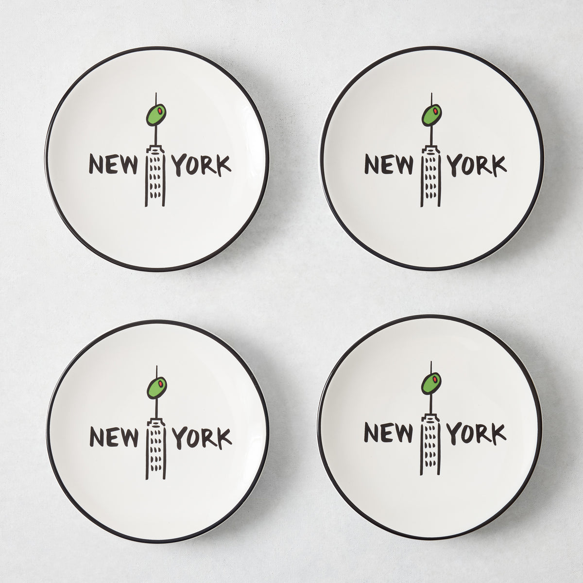 Set of four white appetizer plates with black rims, featuring a hand-painted Empire State Building, olive, and New York text.