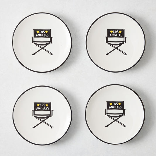 Set of four white appetizer plates with black rims and hand-painted Los Angeles director's chair illustrations.