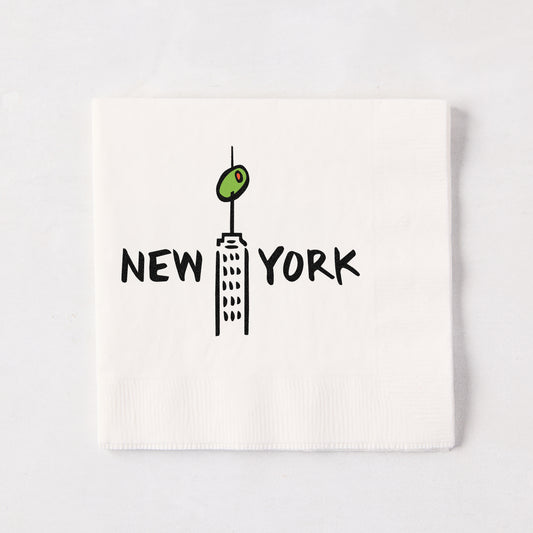 White 5.5-inch 3-ply paper cocktail napkin with a black New York skyscraper illustration topped with a green olive.