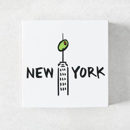 White square matchbox featuring a black line illustration of a New York skyscraper topped with a green olive.