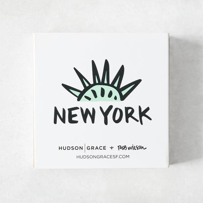 White square matchbox featuring a mint green Statue of Liberty crown illustration and New York text by Rob Wilson.