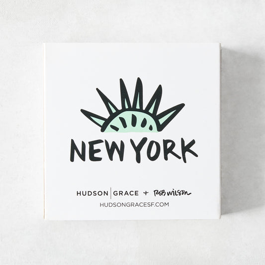 White square matchbox featuring a mint green Statue of Liberty crown illustration and New York text by Rob Wilson.