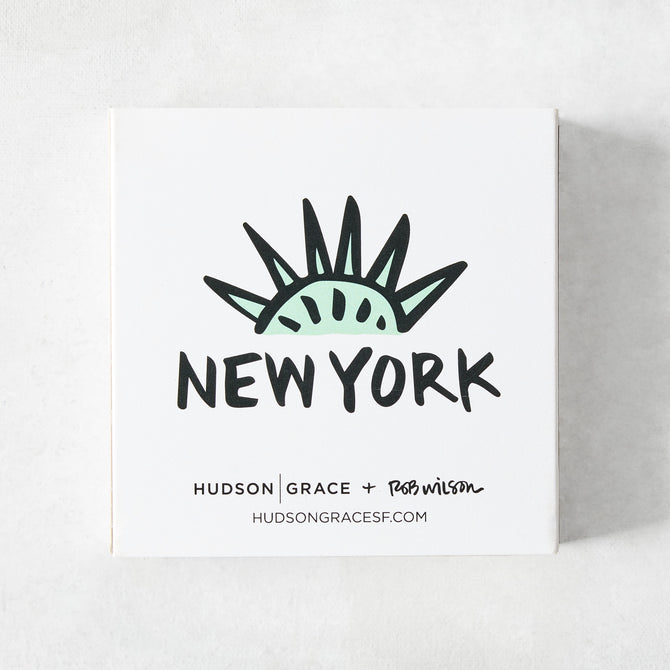 White square matchbox featuring a mint green Statue of Liberty crown illustration and New York text by Rob Wilson.