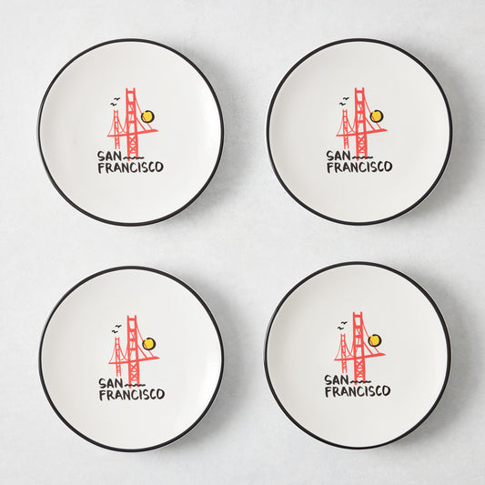 Set of four white appetizer plates with black rims and hand-painted Golden Gate Bridge San Francisco illustrations.