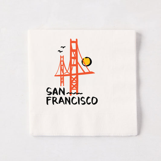 White 5.5-inch square paper cocktail napkin with a red Golden Gate Bridge illustration and San Francisco text.