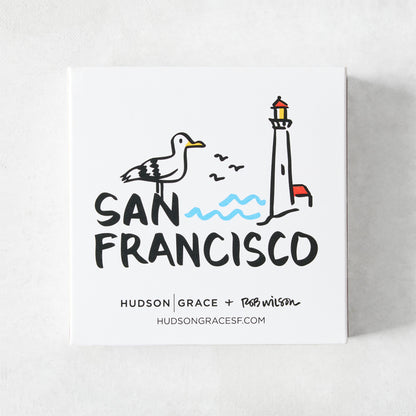 White square matchbox featuring a San Francisco illustration by Rob Wilson with a seagull, lighthouse, and blue waves.