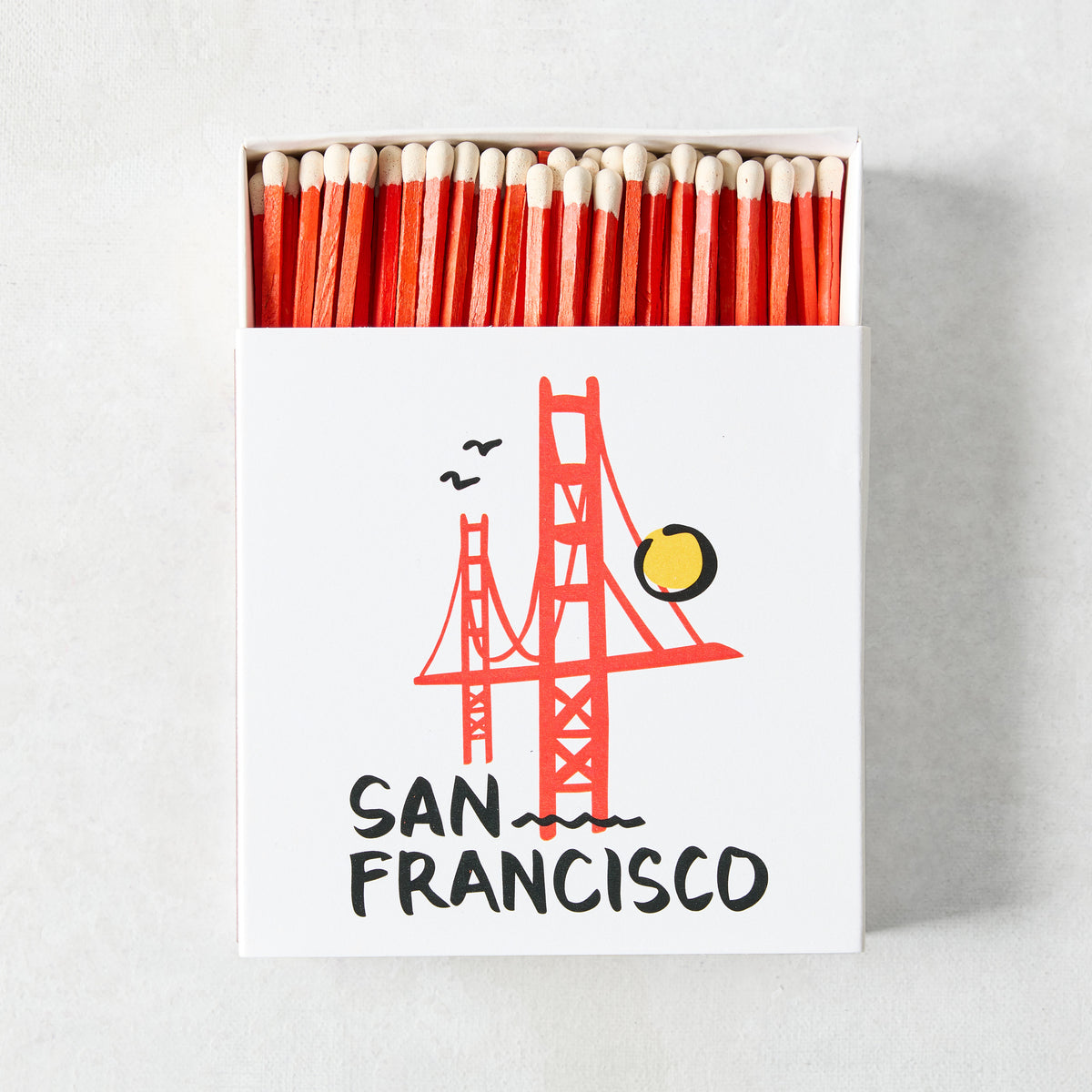 Open box of oversized matches with red tips and a San Francisco Golden Gate Bridge illustration on the white cover.