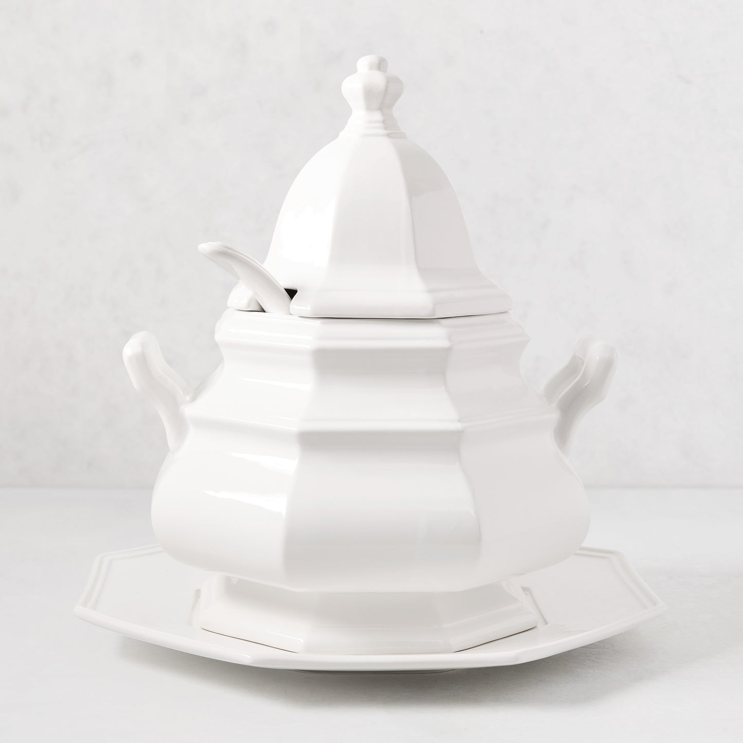 White ceramic Roma soup tureen with lid, spoon notch, handles, and matching octagonal base.