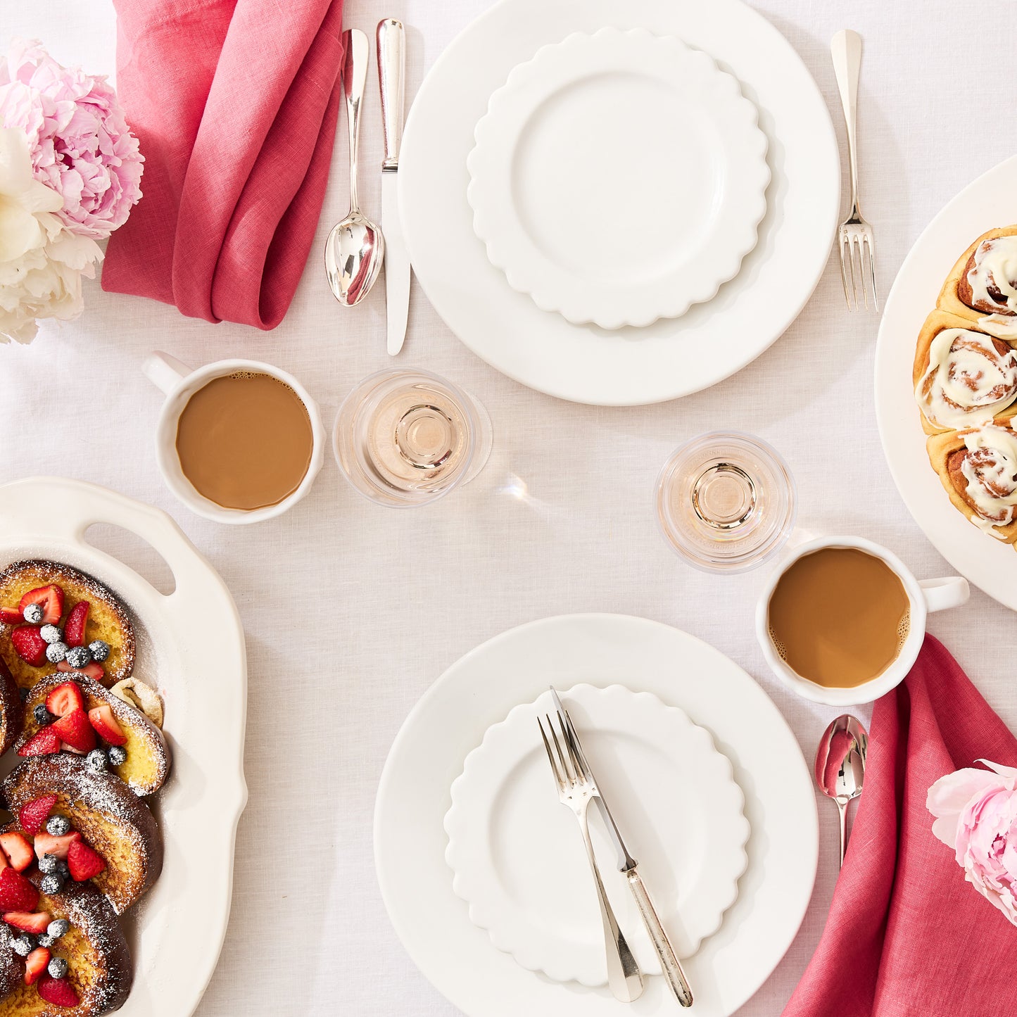 Rosy HG hand-dyed 22" linen napkin, folded on a white dining table with brunch settings.