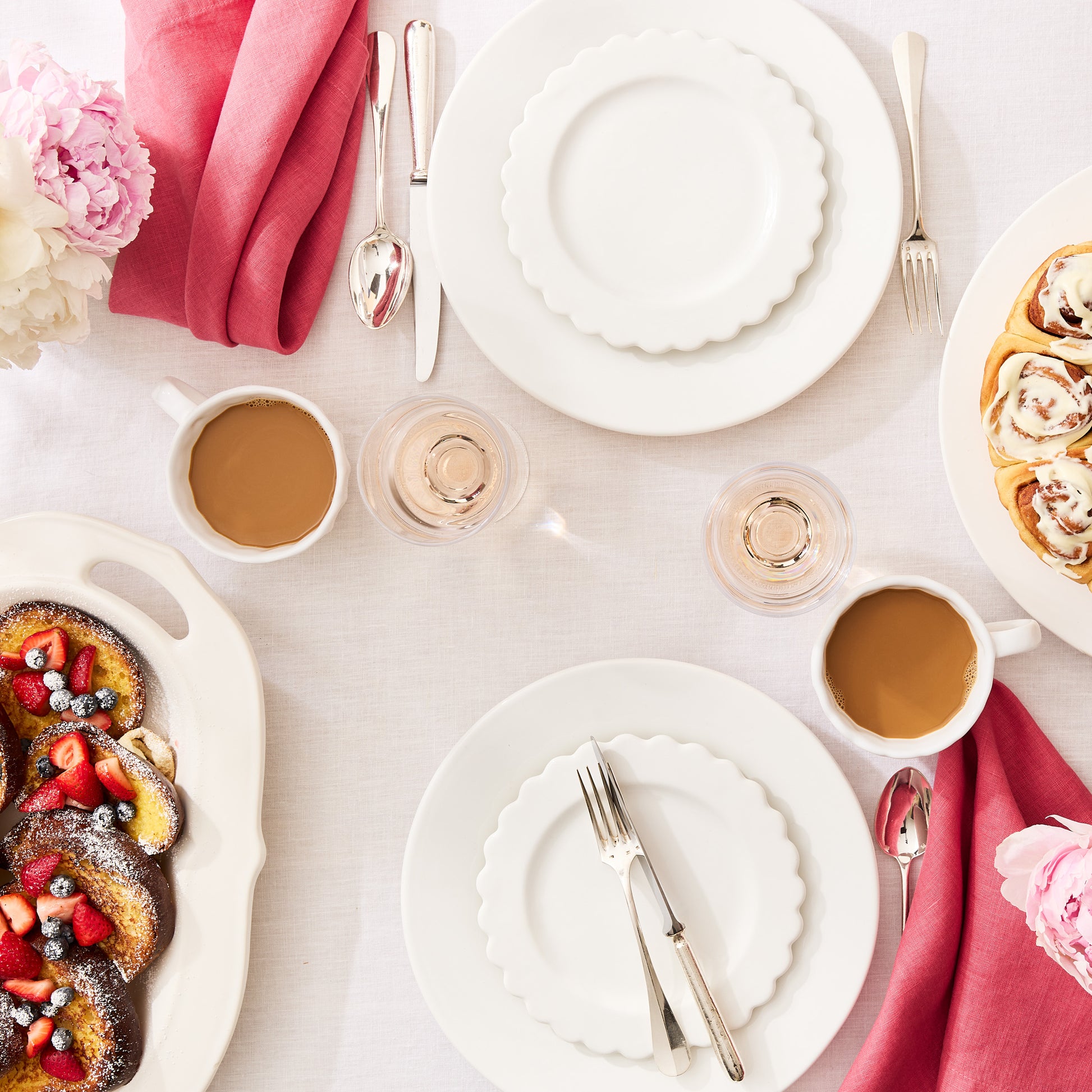 Rosy HG hand-dyed 22" linen napkin, folded on a white dining table with brunch settings.