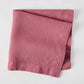 Rosy HG hand-dyed 22" square linen napkin, folded on a white surface.