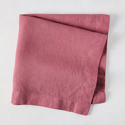 Rosy HG hand-dyed 22" square linen napkin, folded on a white surface.