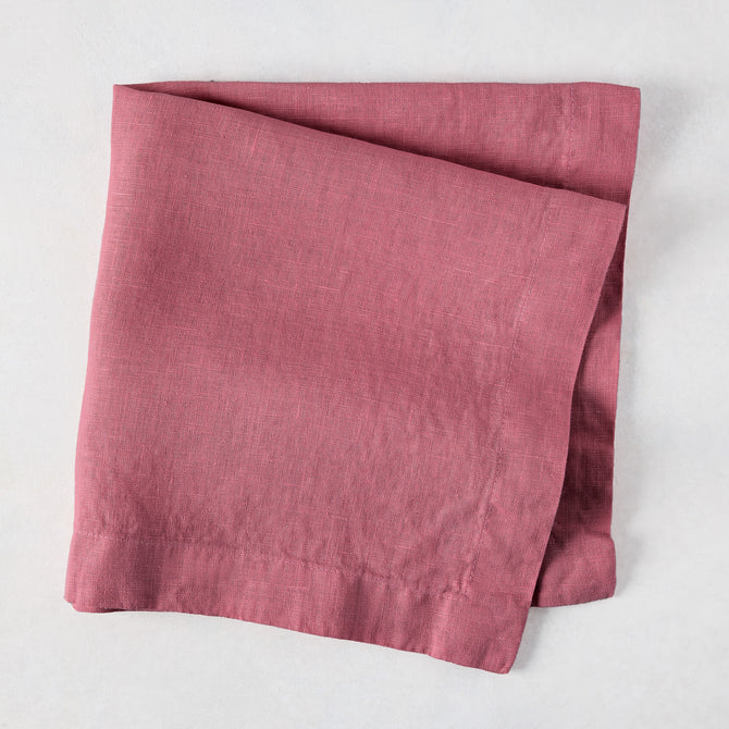 Rosy HG hand-dyed 22" square linen napkin, folded on a white surface.