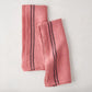 Set of 2 rosy pink French linen tea towels with black stripes, folded on a white surface.