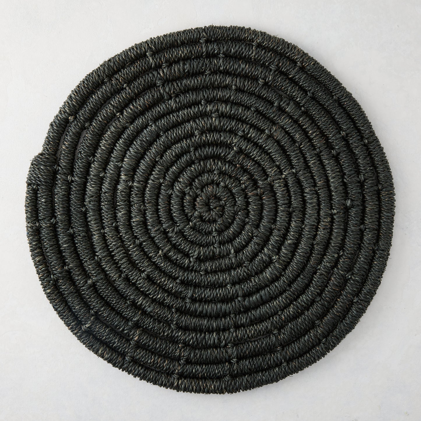 Round black woven abaca placemat, 15" Dia, with concentric spiral design.