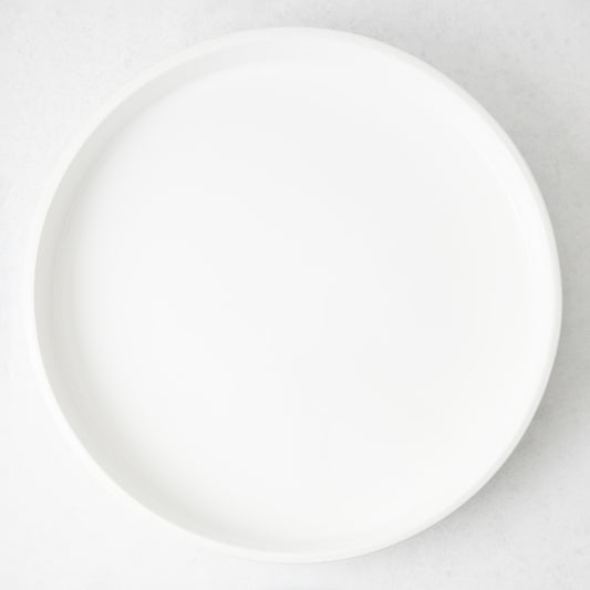 Round white ceramic bar tray with a sleek, minimalist design and low edges, 17.72 inches in diameter.